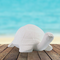 Handmade ready to paint ceramic turtle on a table by the ocean.  It is facing slightly toward the right.  The detail on the shell is visible